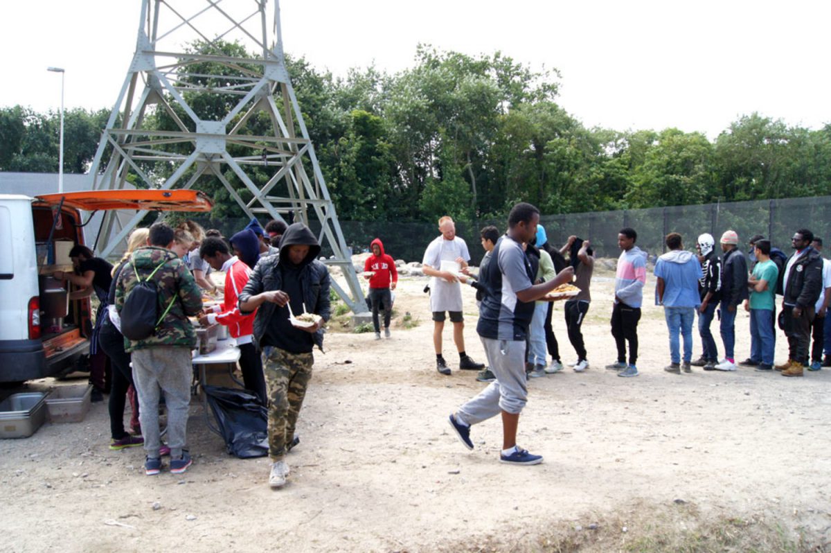 Migrantes reciben comida de una ONG en los alrededores de Calais, casi un año después del desmantelamiento de La Jungla. / Enrico Bonet